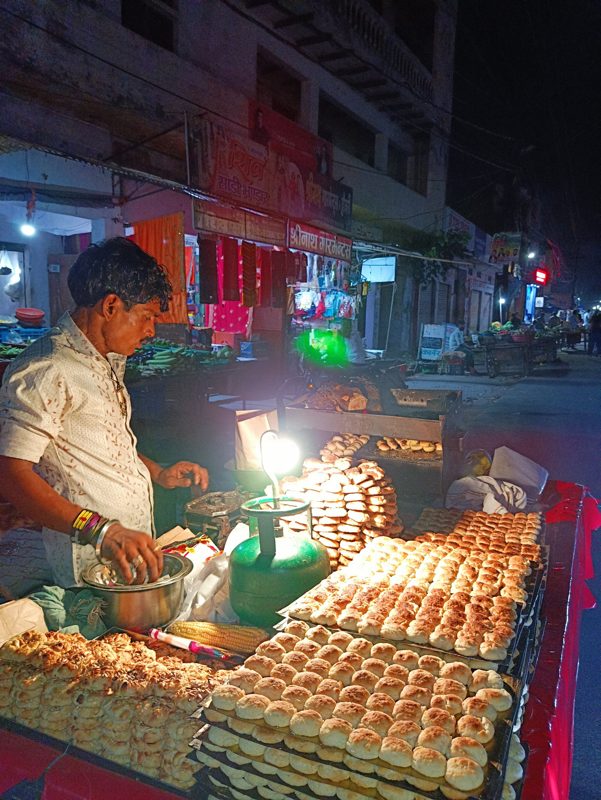 A night-time thela in Firozabad stacked with rows of baked biscuits under a single bulb